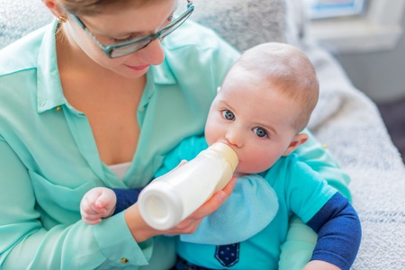 Mother feeding milk to a hungry toddlerの写真素材