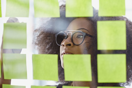 Friendly african american executive business woman brainstorming using adhesive notes in a modern white officeの写真素材