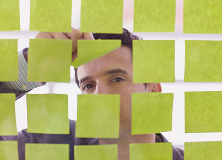 Serious executive business man brainstorming using green adhesive notes in a modern white officeの写真素材