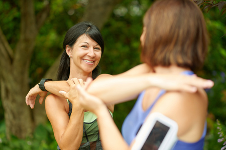 Couple of technology savy women in their forties preparing for a run by streching their musclesの写真素材