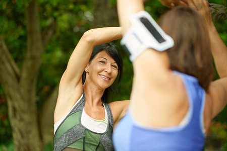 Couple of technology savy women in their forties preparing for a run by streching their musclesの写真素材