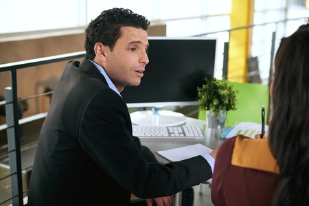 Couple of business coworkers collaborating on a project in a bright glass officeの写真素材