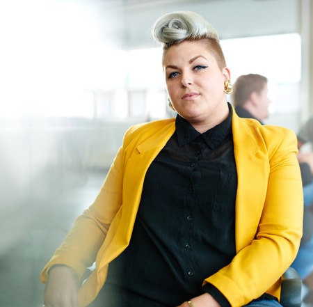 Casual portrait of a business woman using technology in a bright and sunny startup with windows in the backgroundの写真素材