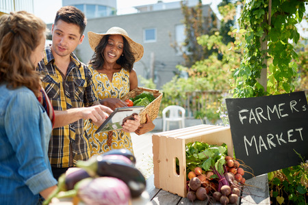 Female gardener selling organic crops and picking up a bountiful basket full of fresh produceの写真素材