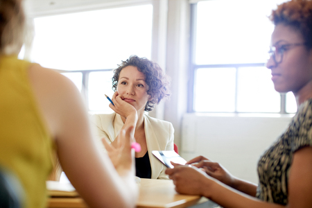 Candid picture of a female boss and business team collaborating. Filtered serie with light flares, bokeh, warm sunny tones.の写真素材