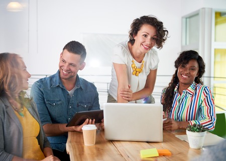 Group of young casual employees discussing a brainstorming project while researching ideas on a computer.の写真素材