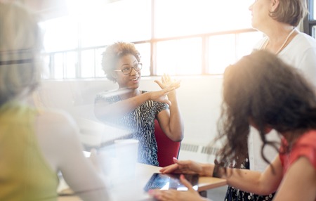 Candid picture of a female boss and business team collaborating. Filtered serie with light flares, bokeh, warm sunny tones.の写真素材