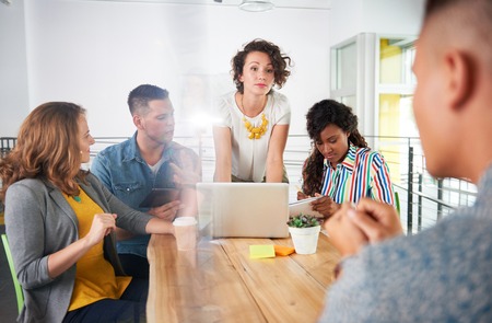 Group of young casual employees discussing a brainstorming project while researching ideas on a computer.の写真素材