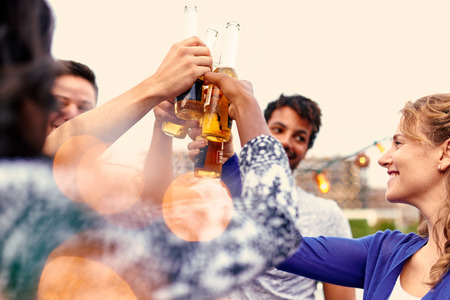 Four young casual friends having fun at an urban party and having a drink with cityscape viewの写真素材