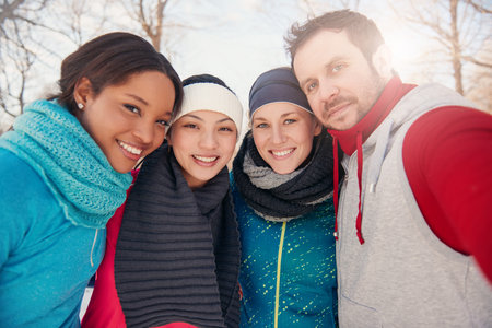 Group of millenial young adult friends enjoying wintertime and in a snow filled park