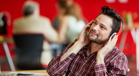 Casual portrait of a business man having a conversation on a cellular phone in a bright and sunny startup with the team in the backgroundの写真素材