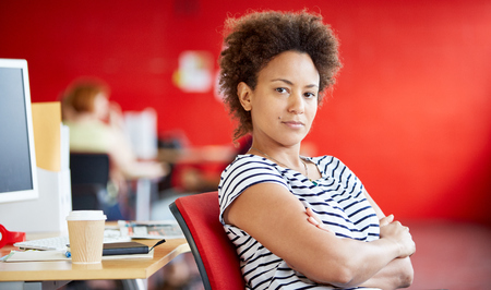 Confident female designer working in red creative office spaceの写真素材