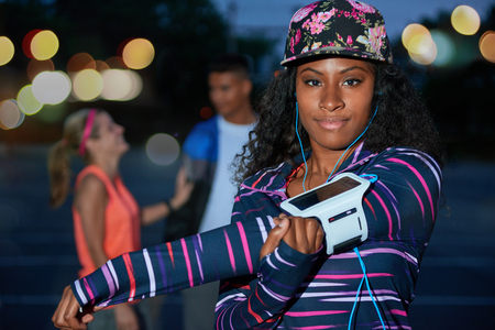 African american millennial girl streching her shoulders outdoors in a urban park late evening with her friends.の写真素材