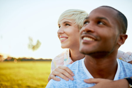 Mixed race couple of millennial in a grass field embracing for a fun tender moment