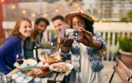 Group of diverse friends taking selfies pictures having dinner al fresco in urban settingの写真素材