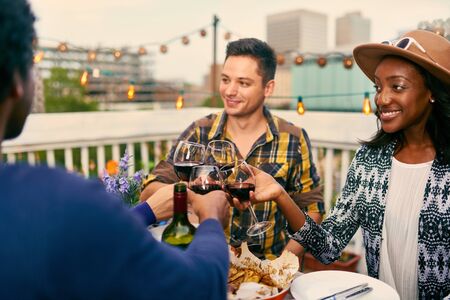 Group of diverse friends having dinner and a glass of wine al fresco in urban settingの写真素材