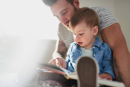 Adorable, young female toddler learning to read book with handsoの写真素材