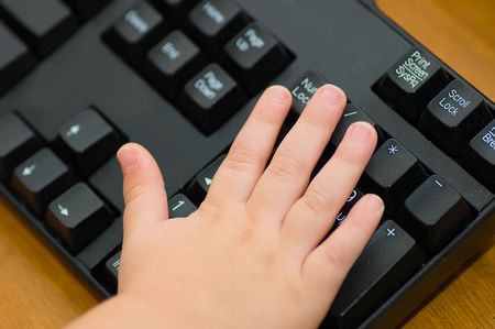 Toddler hand on black computer keyboardの写真素材
