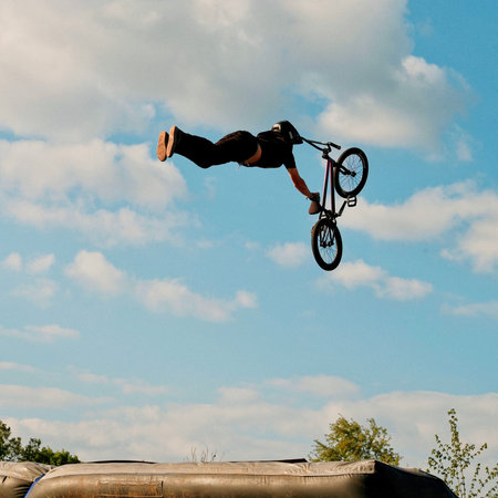 A BMX rider jumps over a trampoline in a jump.