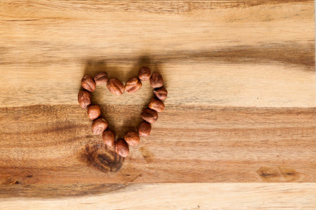 Heart made of hazelnuts on wooden background.の写真素材