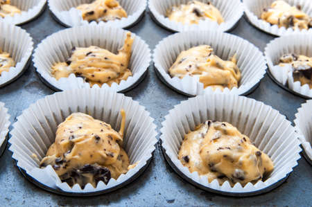 Closeup of raw chocolate chip cupcake dough in cupcake try ready to go in the oven. A cupcake is a small cake designed to serve one person.の写真素材
