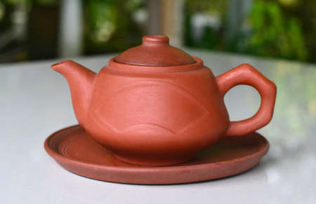 Clay teapot on the round clay plate, side viewの写真素材