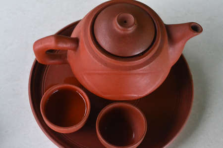 Clay teapot and two little cups on the round clay plate, top viewの写真素材