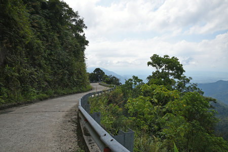 Serpentine mountain road with fence, mountain view and city awayの写真素材