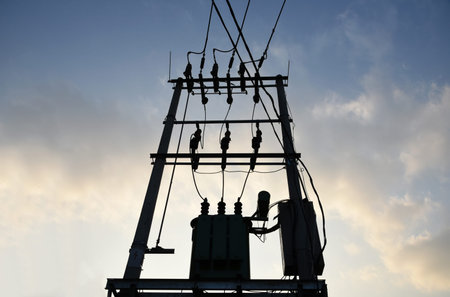 Electric pole with transformer and power line cables against the background of the evening sky