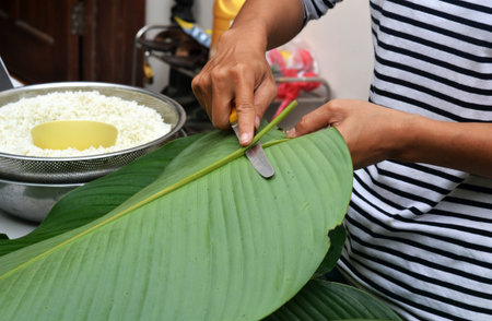 A man cuts a stalk off a banana leaf to make a Vietnamese New Year Banh Chung cake