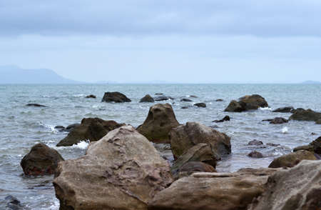 View from the rocky coast to the sea, islands on the horizon, large stones in the foregroundの写真素材