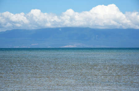 View from the sea to the island under white cloudsの写真素材