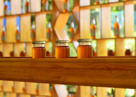Three jars of honey standing on a wooden shelf in a honey storeの写真素材