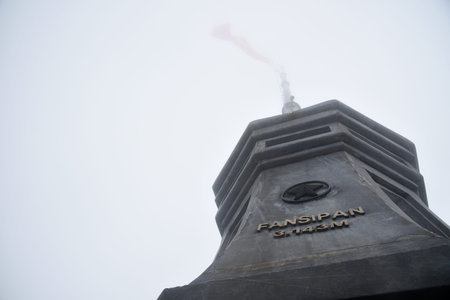 Monument at the top of Mount Fansipan with the Vietnamese flag, almost invisible due to the cloud,...