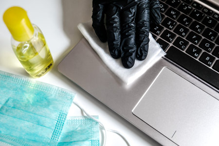 Cleaning laptop with antibacterial wet wipes to prevent virus spreading and kill bacteria. Personal...