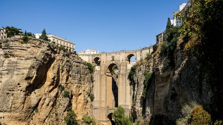 Puente Nuevo famous new bridge in the heart of old village Ronda in Andalusia, Spain. Touristic landmark on a sunny day with buildings in the background. Front view captured from a viewpoint below.の写真素材