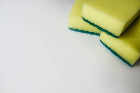 Cleaning facilities during coronavirus outbreak isolation. Yellow dish washing sponges. Everyday housewife kitchen equipment and essential tools. Setting on a white surface with empty space for copy.の写真素材
