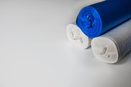 Blue and white plastic trash bags on a white surface. Recyclable materials to protect environment. Cleaning facilities during coronavirus isolation. Empty space for copy. Plastic planet pollution.の写真素材