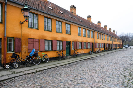 Empty deserted street in a European popular capital Copenhagen, Denmark. Bright orange painted beautiful buildings. Hygge houses without people. Colorful city landscape with nobody around.の写真素材