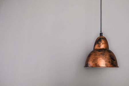 Antique decorative brown bronze shimmer lamp hanging from the ceiling. Grey wall in the background with empty space for text, copy or ideas. Modern apartment renovation and home interior decor.の写真素材