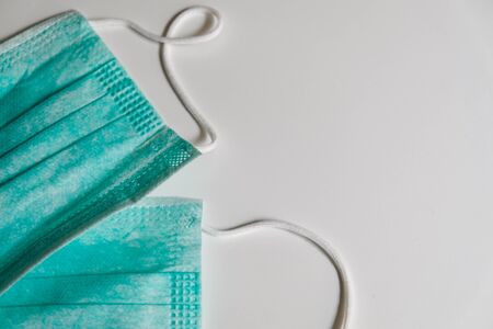 Two standard blue face medical masks on a white table. Self protection from virus, bacteria, sickness, corona or flu. Prevention methods during quarantine isolation. Staying safe and healthy at home.の写真素材