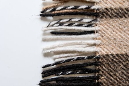 Brown plaid blanket with long edges. Close up view on a white surface. Textile in interior design. Warming up cozy material to cover up when studying or working from home in isolation. Fall vibes.の写真素材