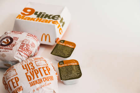 Lviv / Ukraine - April 2020: Unhealthy eating at home during coronavirus outbreak isolation. Takeaway Mcdonalds meal on a table. Ukrainian version of chicken Mcnuggets, and cheeseburgers. White space.のeditorial素材