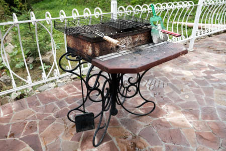 Barbecue grill in the backyard outside. Empty dirty kitchen equipment after cooking dinner. Black grill with charcoal. No bbq celebration during pandemic. Unhealthy lifestyle for non-vegan people.の写真素材