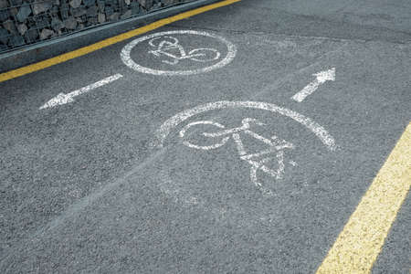 Bicycle lane. White road markup signal on concrete asphalt. Transportation restrictions on the way. No pedestrians allowed, no walking, riding bikes only. Red painted crossed sign with person inside.の写真素材