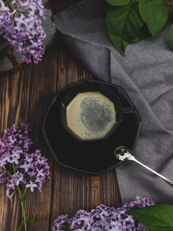 Coffee cup on a wooden background with lilac branches