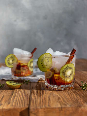 Summer drink with pieces of fruit and ice cubes in a glass on a wooden backgroundの写真素材