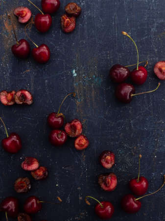 dark summer modern background with red cherry berries and halvesの写真素材