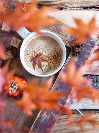 Autumn still life with a cup of coffee and autumn leaves on a wooden backgroundの写真素材
