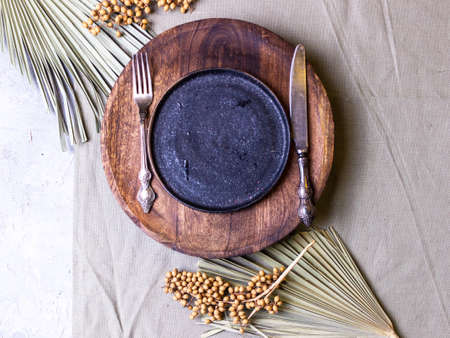 A round plate on a wooden stand with a knife and a forkの写真素材